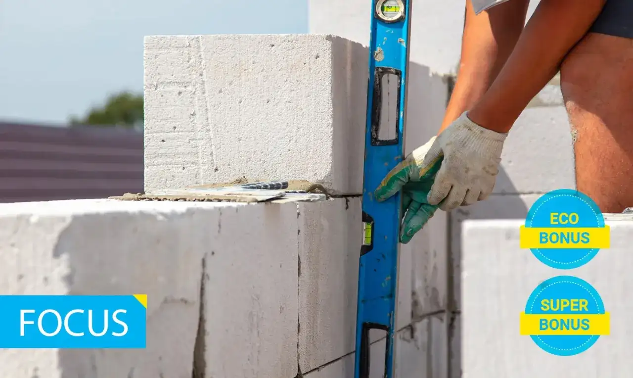 Costruzione con blocchi di calcestruzzo aerato autoclavato, livella in mano per un lavoro preciso. Eco e Super Bonus in evidenza.